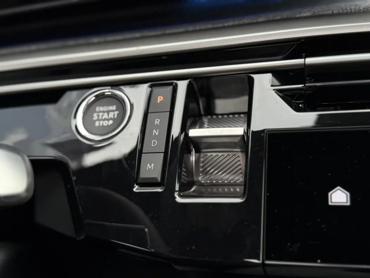 Gros plan sur la console centrale noire brillante du Peugeot 3008 Hybrid avec bouton start/stop et commandes de boîte automatique.