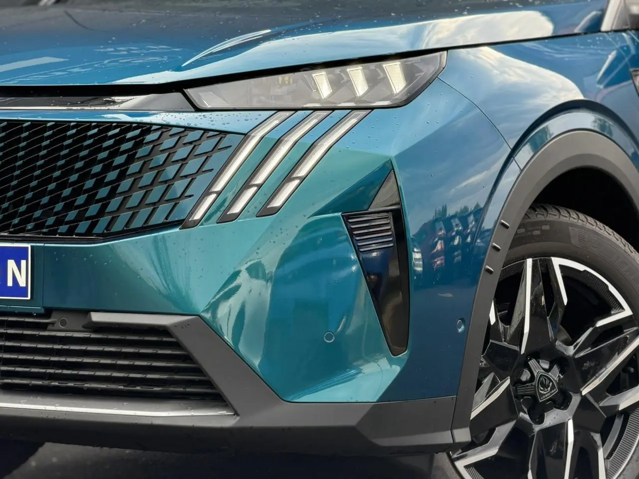 Gros plan sur l'avant droit bleu Obsession du Peugeot 3008 Hybrid 145 GT avec phares à griffes LED et jante alliage noire.
