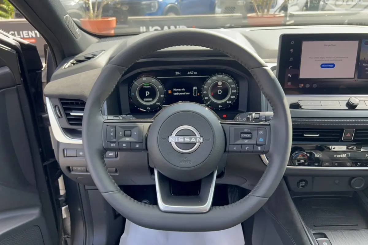 Vue centrée sur le volant cuir Nissan du Qashqai E-Power 205 Tekna Plus avec tableau de bord numérique et écran tactile.