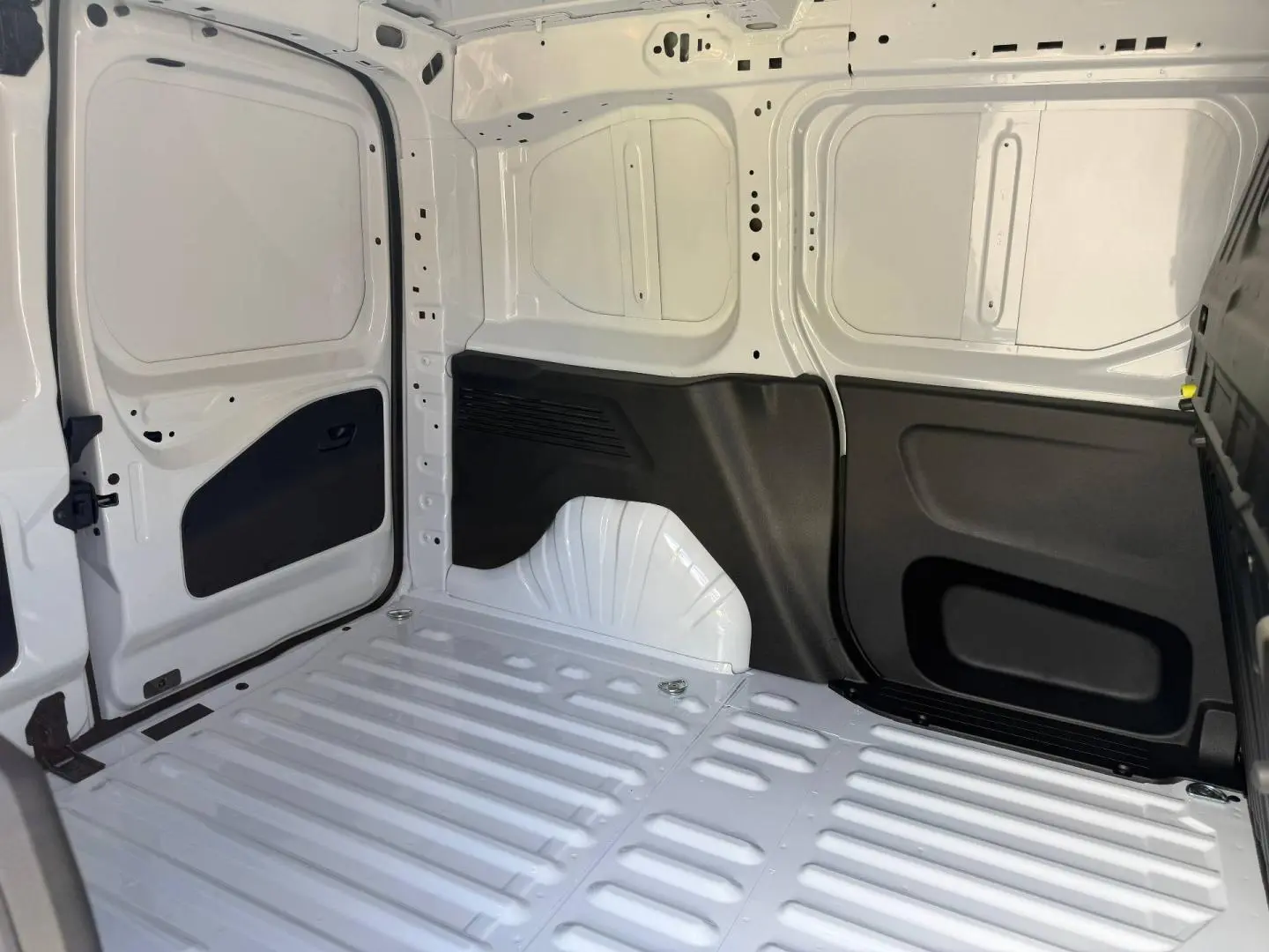 Vue intérieure de la zone de chargement arrière du Peugeot Partner blanc Icy, avec parois et sol métalliques visibles.