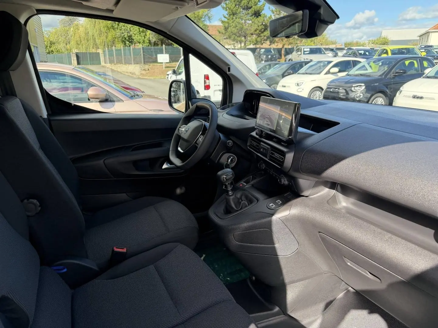 Intérieur du Peugeot Partner 2026 vu côté conducteur, montrant sièges noirs et tableau de bord avec écran tactile.