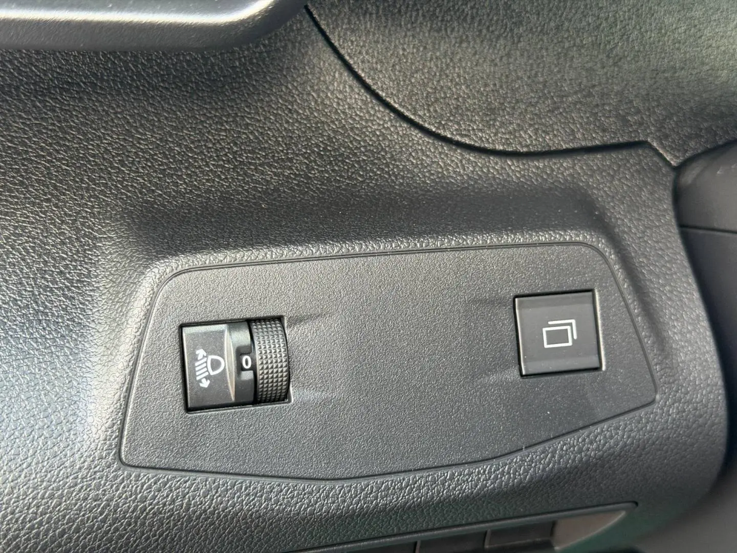 Gros plan sur les commandes noires de réglage des phares et du rétroviseur dans un Peugeot Partner blanc Icy 2026.