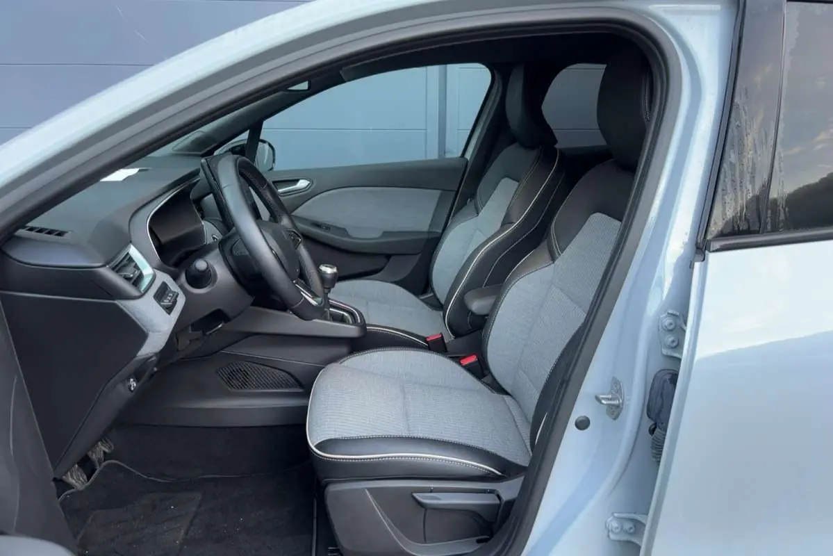 Vue intérieure côté conducteur de la Renault Clio gris rafale 2025 avec sièges bi-matière et volant cuir.