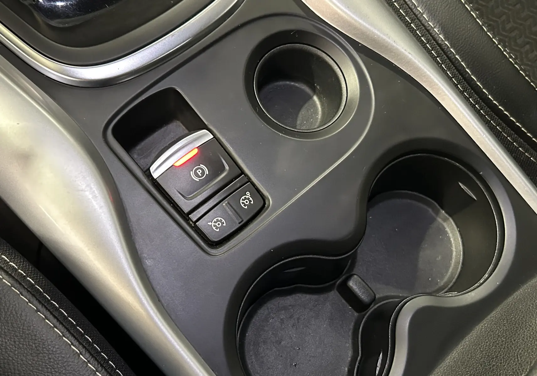 Gros plan sur la console centrale du Renault Kadjar TCe 130 avec frein à main électronique et porte-gobelets noirs.