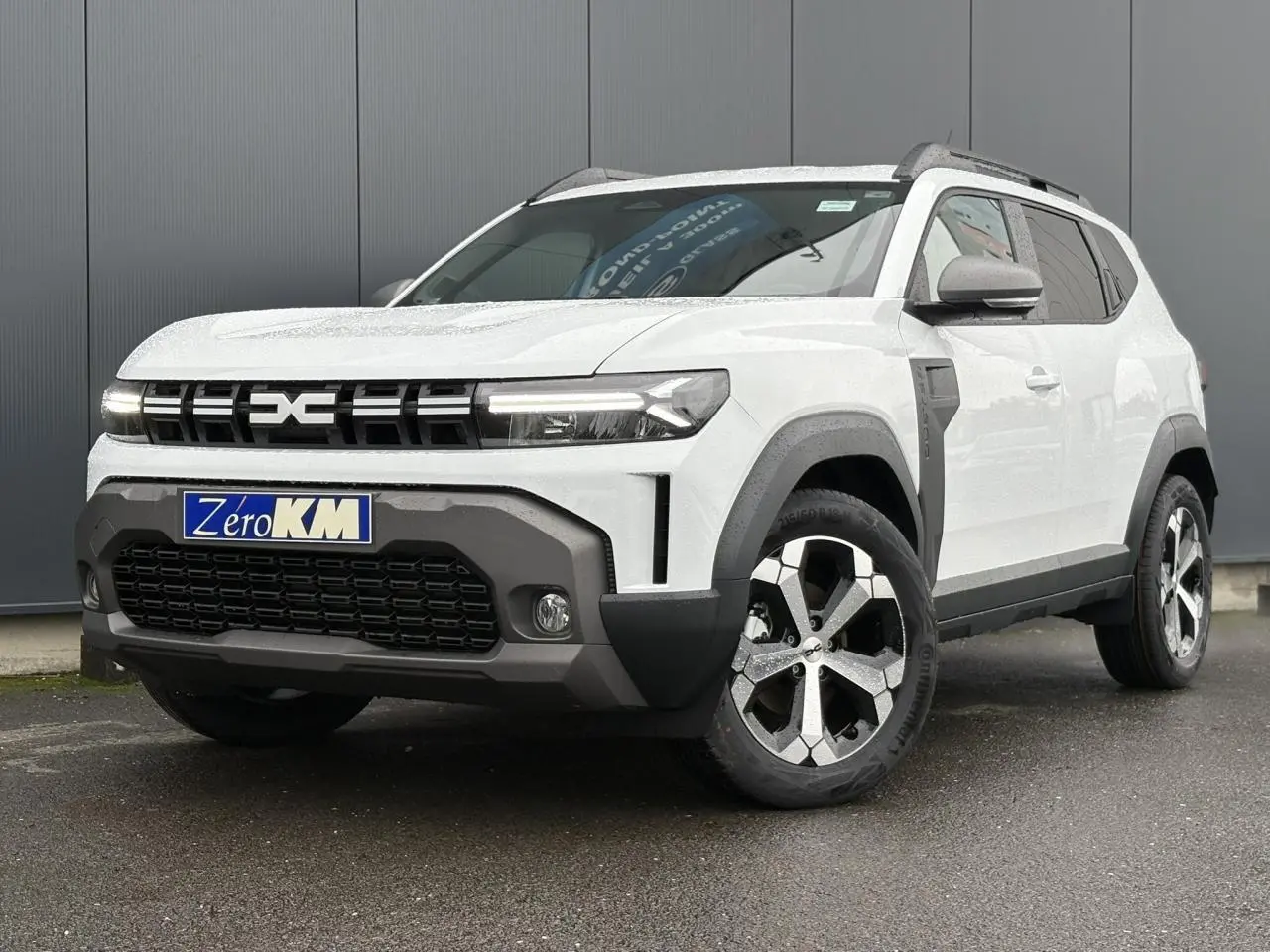 SUV Dacia Duster blanc glacier vu en 3/4 avant droit, avec calandre noire et jantes alliage bicolores.