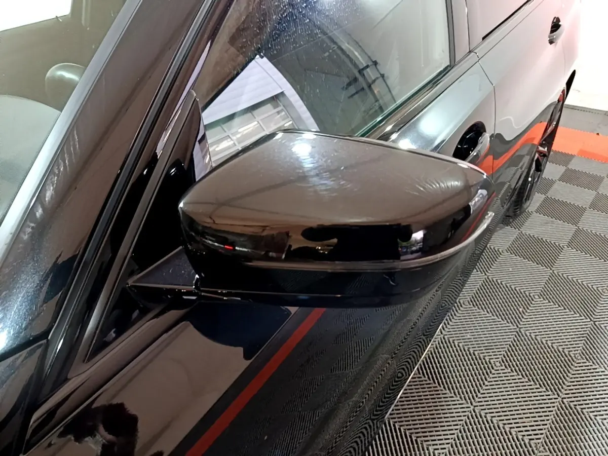 Rétroviseur côté gauche noir brillant d'une BMW Série 3 318i M Sport 2022, vue rapprochée sur la portière et la vitre.