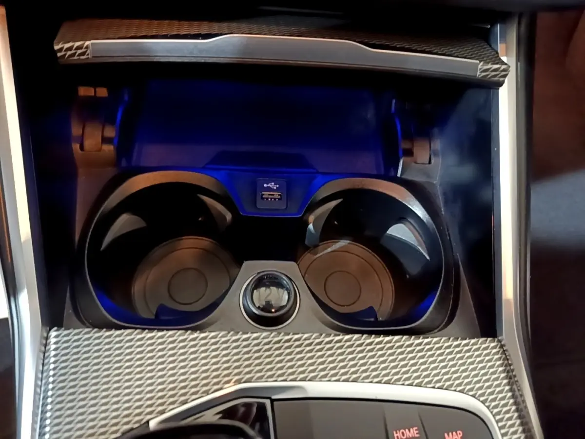 Gros plan sur la console centrale noire de la BMW Série 3 318i M Sport 2022 avec porte-gobelets et port USB.