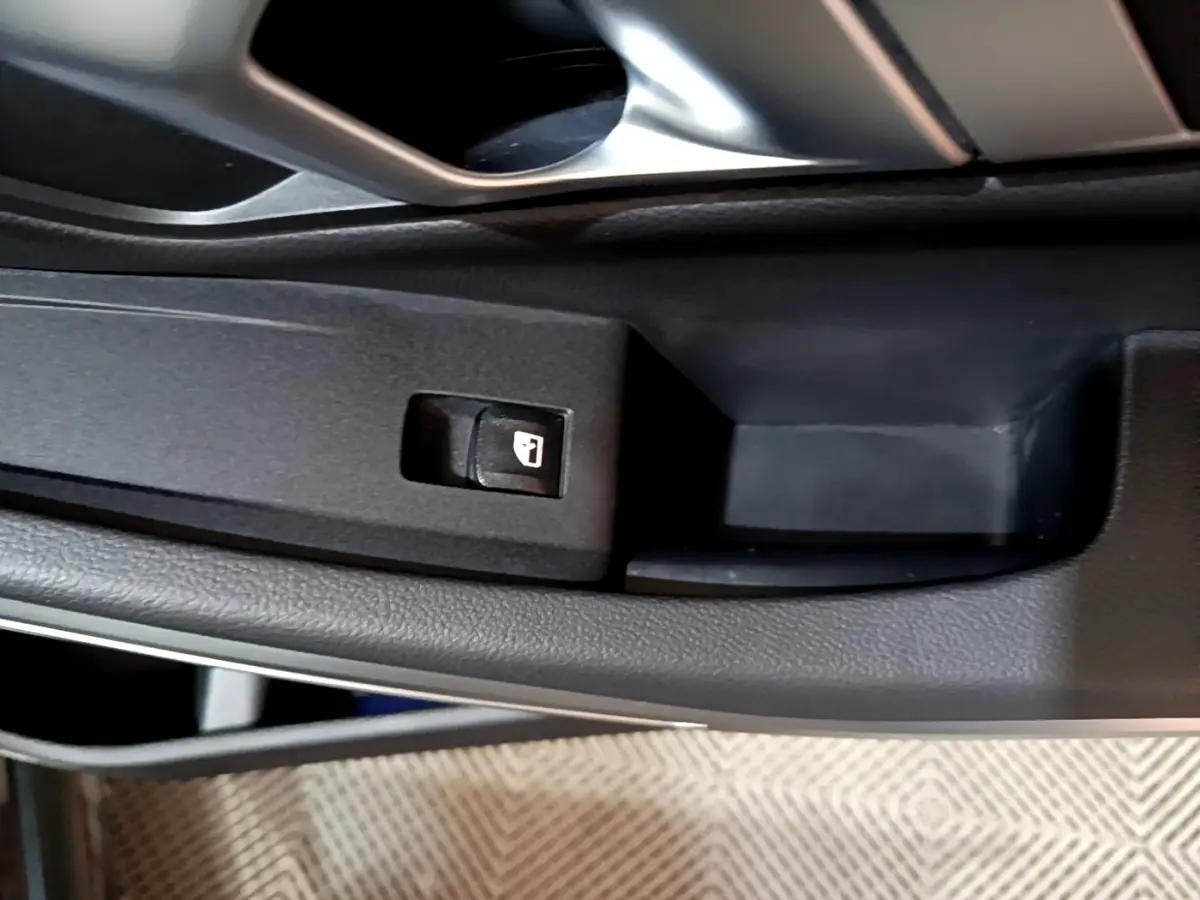Gros plan sur le bouton de verrouillage des portes côté conducteur dans l'intérieur noir de la BMW Série 3 318i M Sport 2022.
