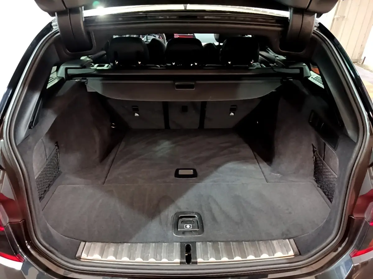 Coffre ouvert d'une BMW Série 3 noire, vue arrière montrant un espace de chargement spacieux et bien fini.