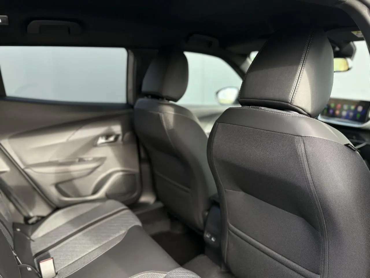Vue intérieure arrière droite du Peugeot 2008 Hybrid 145 e-DSC6 Allure avec sièges tissu noir et détails gris.
