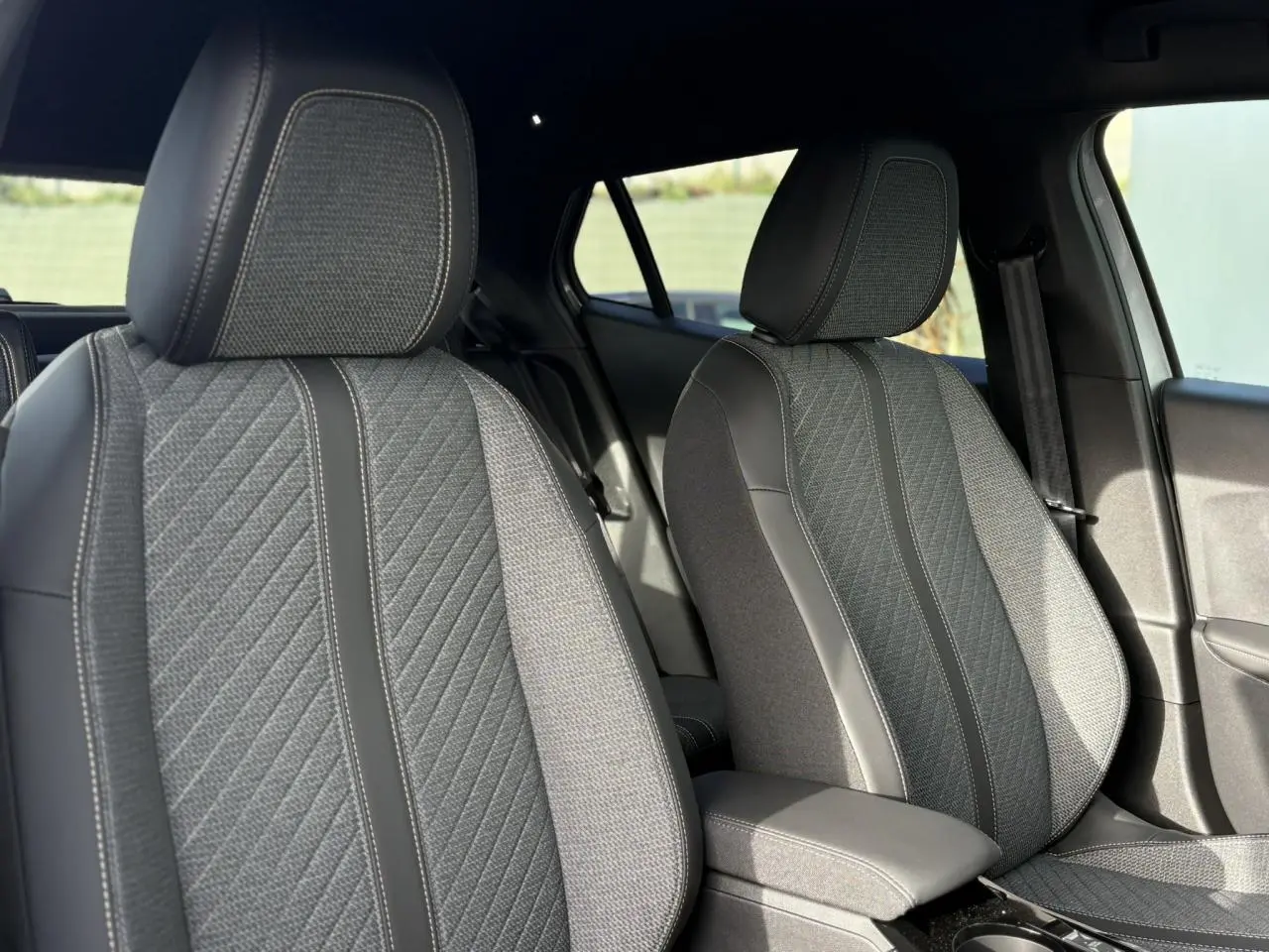 Gros plan sur les sièges avant gris et noirs du Peugeot 2008 Hybrid 145 e-DSC6 Allure, intérieur sobre et moderne.