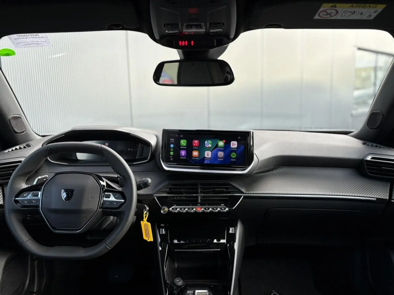 Vue frontale de l'habitacle noir du Peugeot 2008 Hybrid 145 avec écran tactile et volant compact cuir.