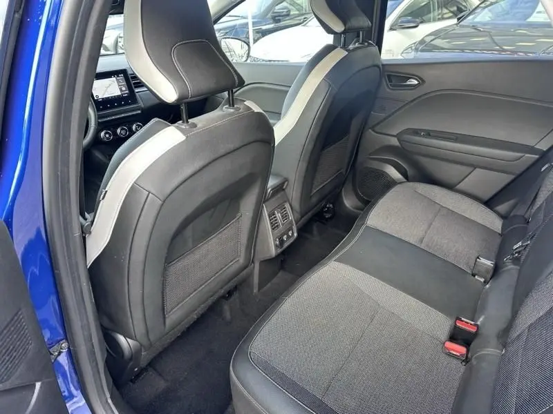 Vue intérieure arrière du Renault Captur bleu métal 2022, montrant les sièges arrière et les dossiers avant avec aérateurs centraux.