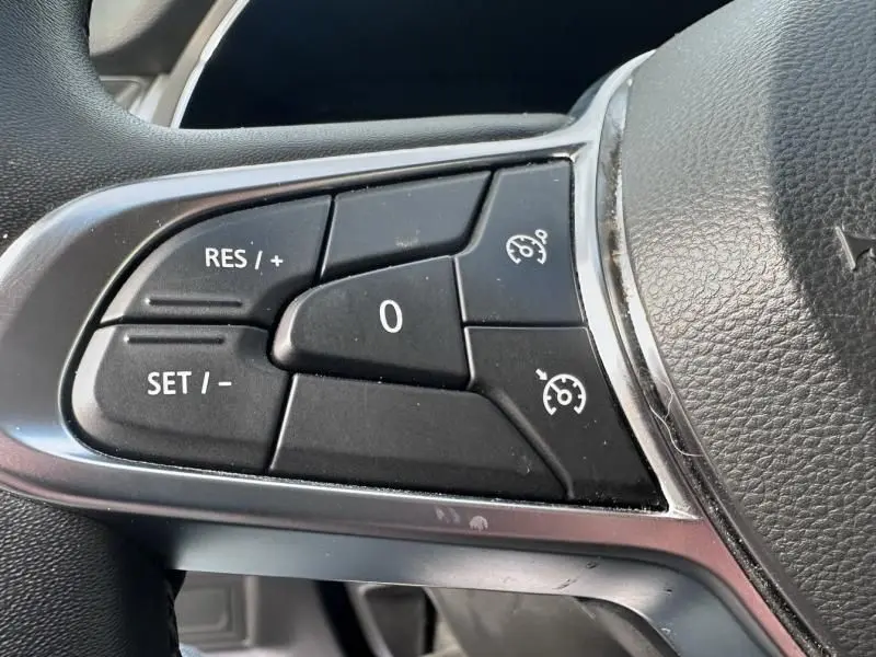 Gros plan sur les commandes de régulateur de vitesse au volant du Renault Captur bleu métal 2022, version hybride.