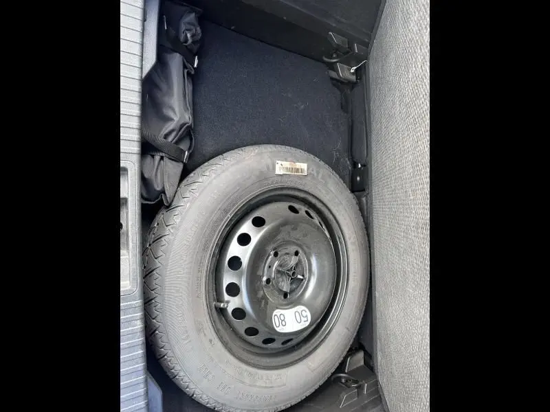 Vue plongeante sur la roue de secours noire dans le coffre du Renault Captur bleu métal 2022 hybride.