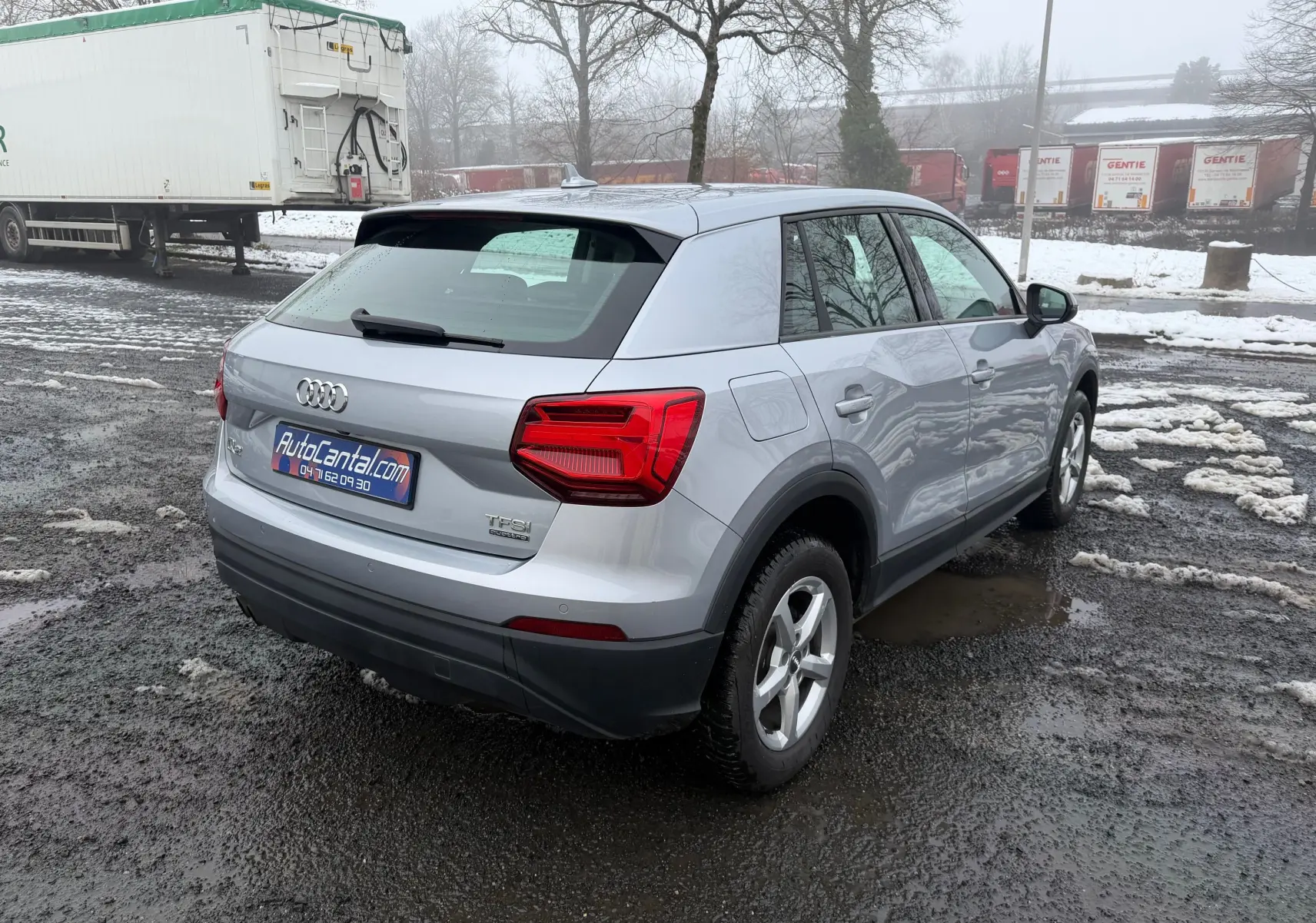 Vue 3/4 arrière droite d'un Audi Q2 gris aluminium 2017 avec feux arrière LED et jantes alliage 17 pouces.
