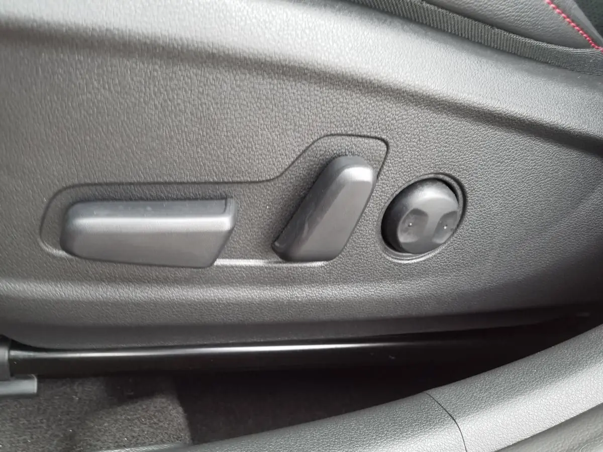 Gros plan sur les commandes électriques de réglage du siège conducteur du Hyundai Kona 2023 finition N Line rouge.