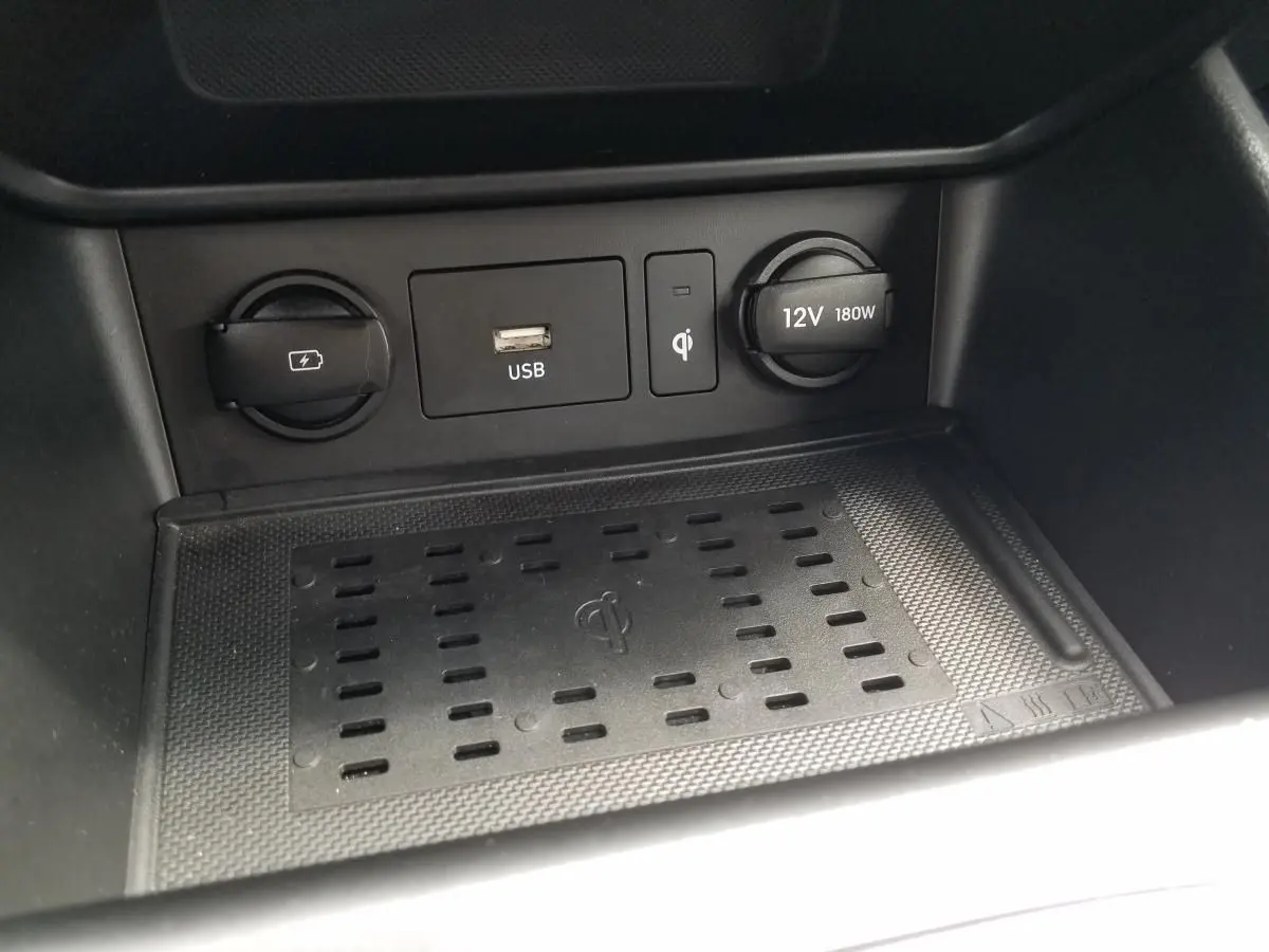 Vue rapprochée de la console centrale du Hyundai Kona rouge 2023, montrant les prises USB, 12V et chargeur sans fil.