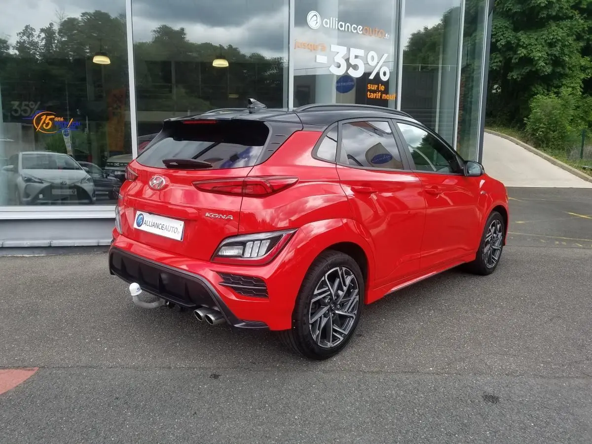 Vue 3/4 arrière droite d'un Hyundai Kona rouge avec toit noir et jantes alliage bi-ton 18 pouces N Line.
