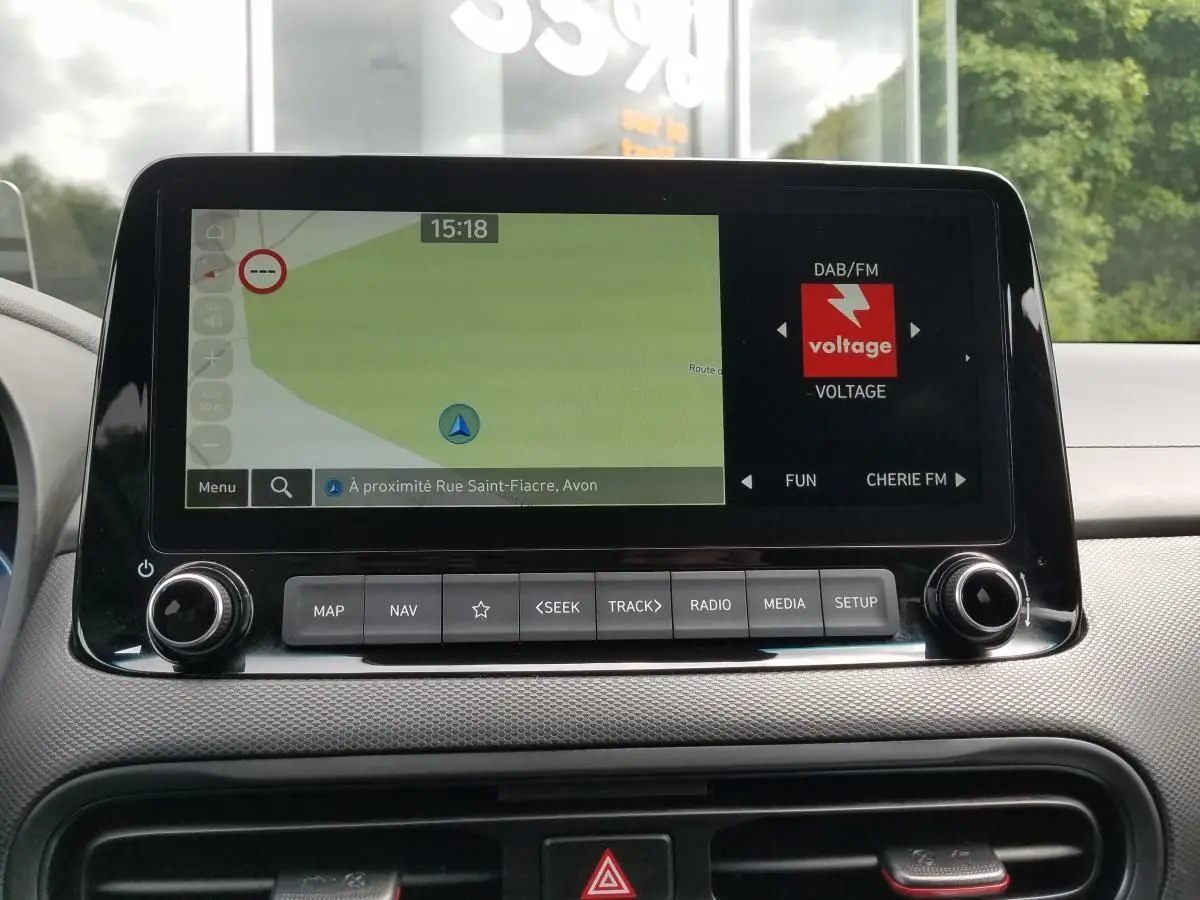 Écran central tactile du Hyundai Kona 2023 affichant la navigation et la radio, vue intérieure frontale.