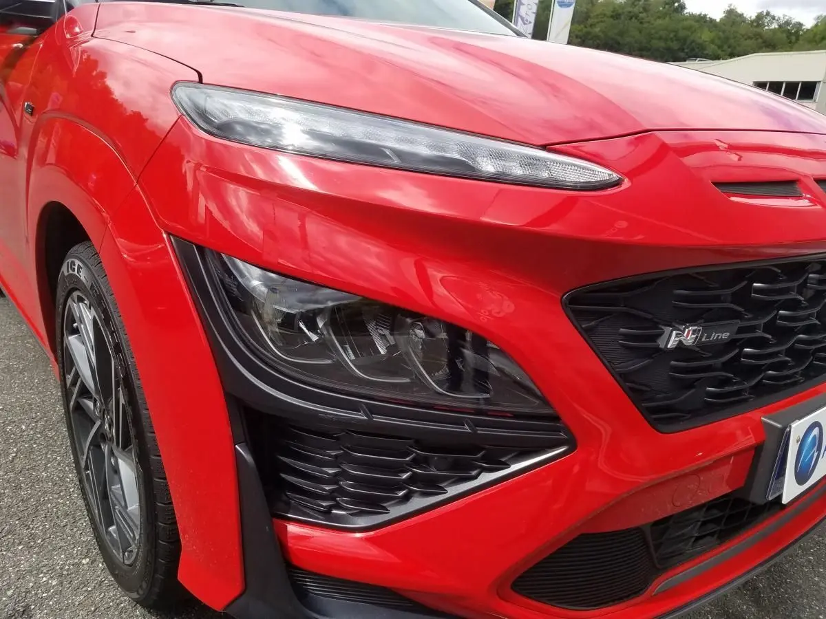 Gros plan sur l'avant droit rouge vif du Hyundai Kona N Line 2023 avec phares bi-LED et calandre noire distinctive.