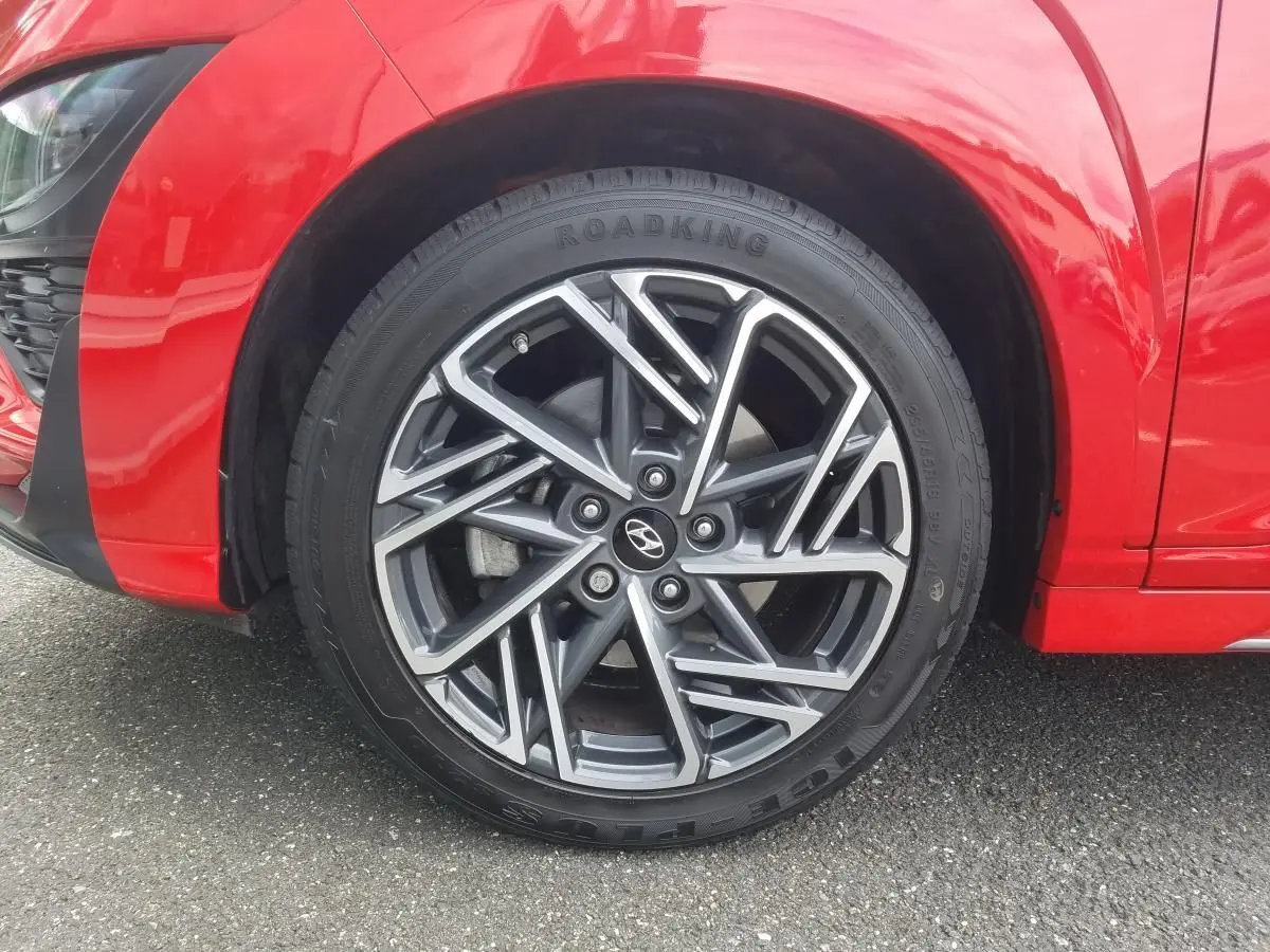 Gros plan sur la jante alliage bi-ton 18'' du côté avant gauche d’un Hyundai Kona rouge 2023.