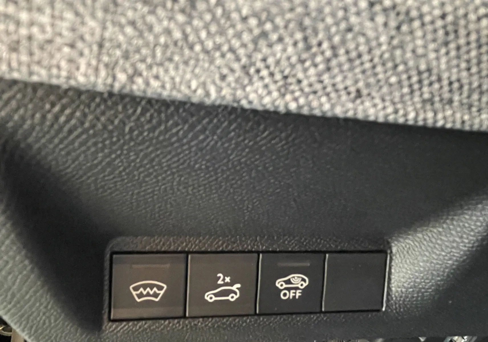 Gros plan sur les boutons de commande intérieurs noirs du Peugeot 3008 Hybrid 145, avec symbole pare-brise chauffant et ouverture coffre.