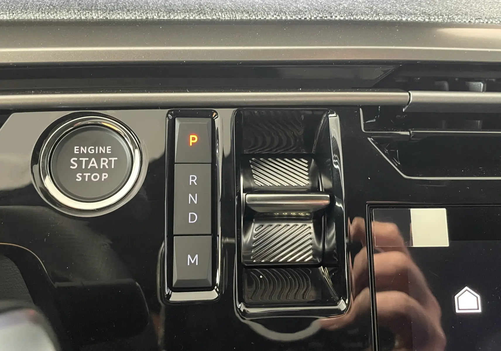 Gros plan sur la console centrale noire du Peugeot 3008 Hybrid 2026, avec bouton start/stop et sélecteur de vitesses électronique.