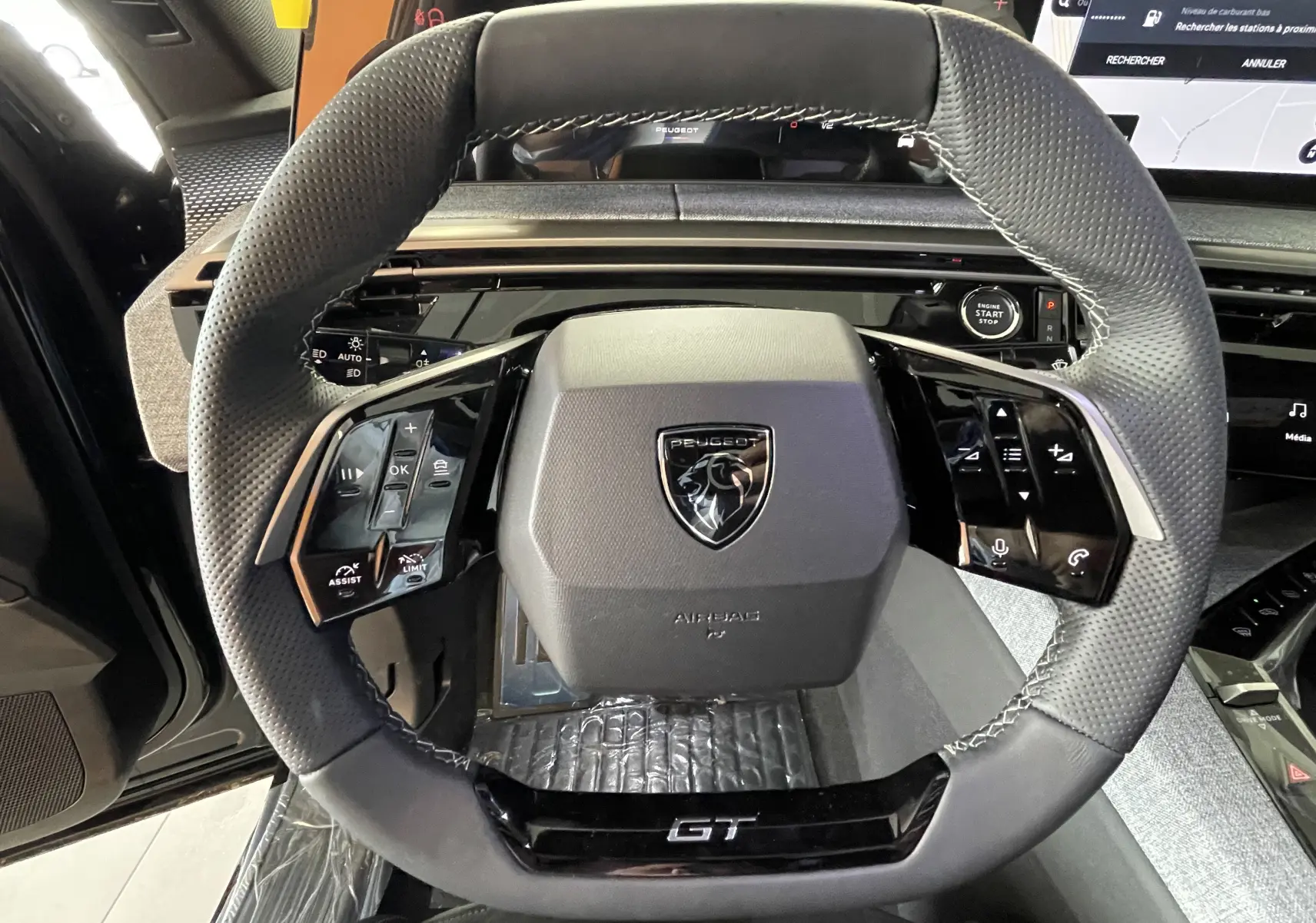 Vue rapprochée du volant noir GT du Peugeot 3008 Hybrid avec commandes intégrées et logo central.