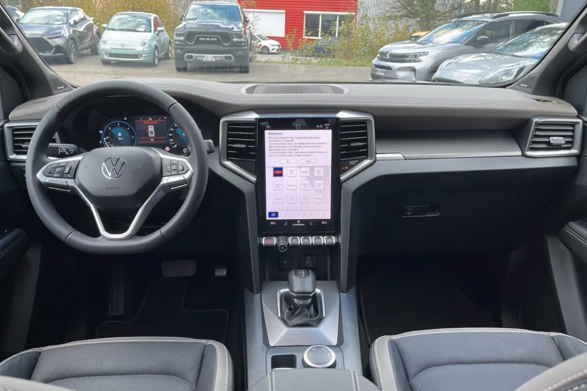 Vue intérieure frontale du Volkswagen Amarok Simple Cabine noir 2025, avec tableau de bord digital et écran tactile vertical.