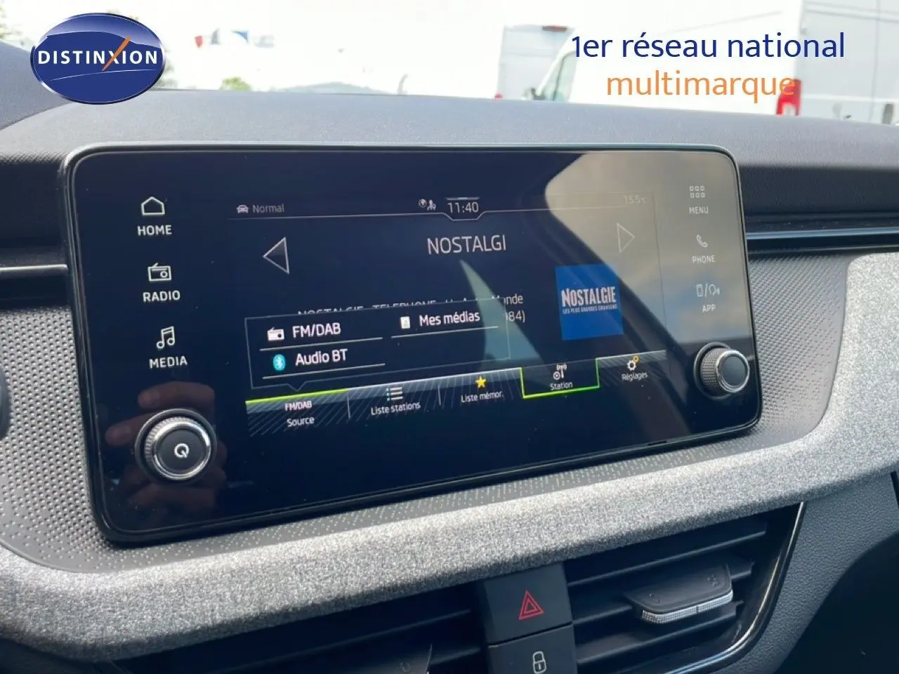 Écran tactile central du tableau de bord de la Skoda Scala blanc glacier, affichant la radio Nostalgie en FM/DAB.