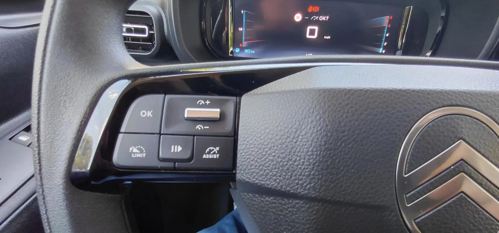 Gros plan sur le volant multifonctions noir du Citroën Berlingo 2025, avec commandes de limiteur et assistance.