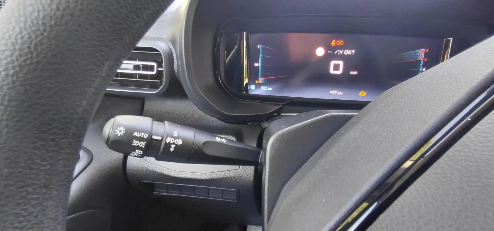 Vue rapprochée du tableau de bord du Citroën Berlingo 2025 essence, avec écran numérique et commande d’allumage automatique.