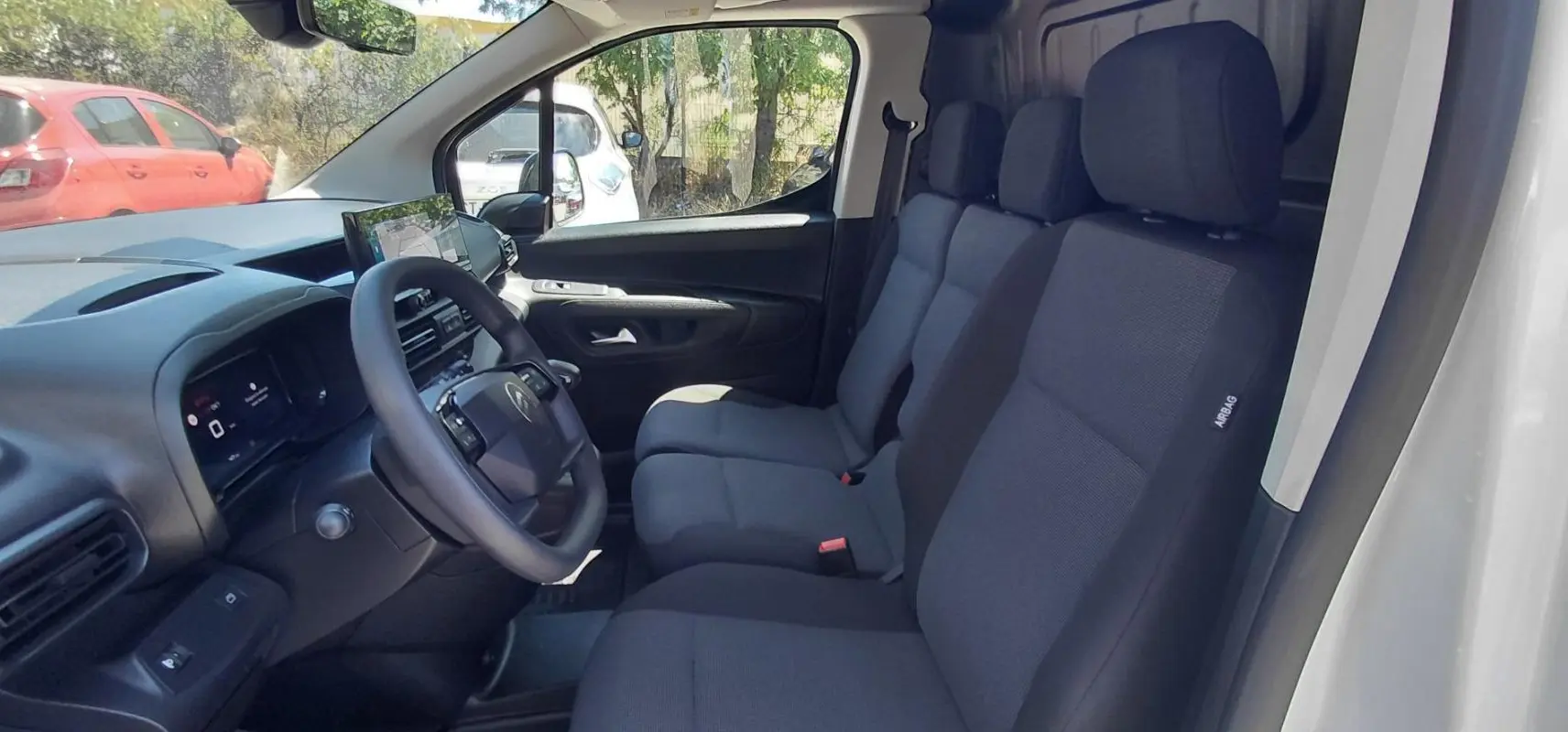 Vue intérieure côté conducteur du Citroën Berlingo blanc 2025, montrant les sièges avant et le tableau de bord.