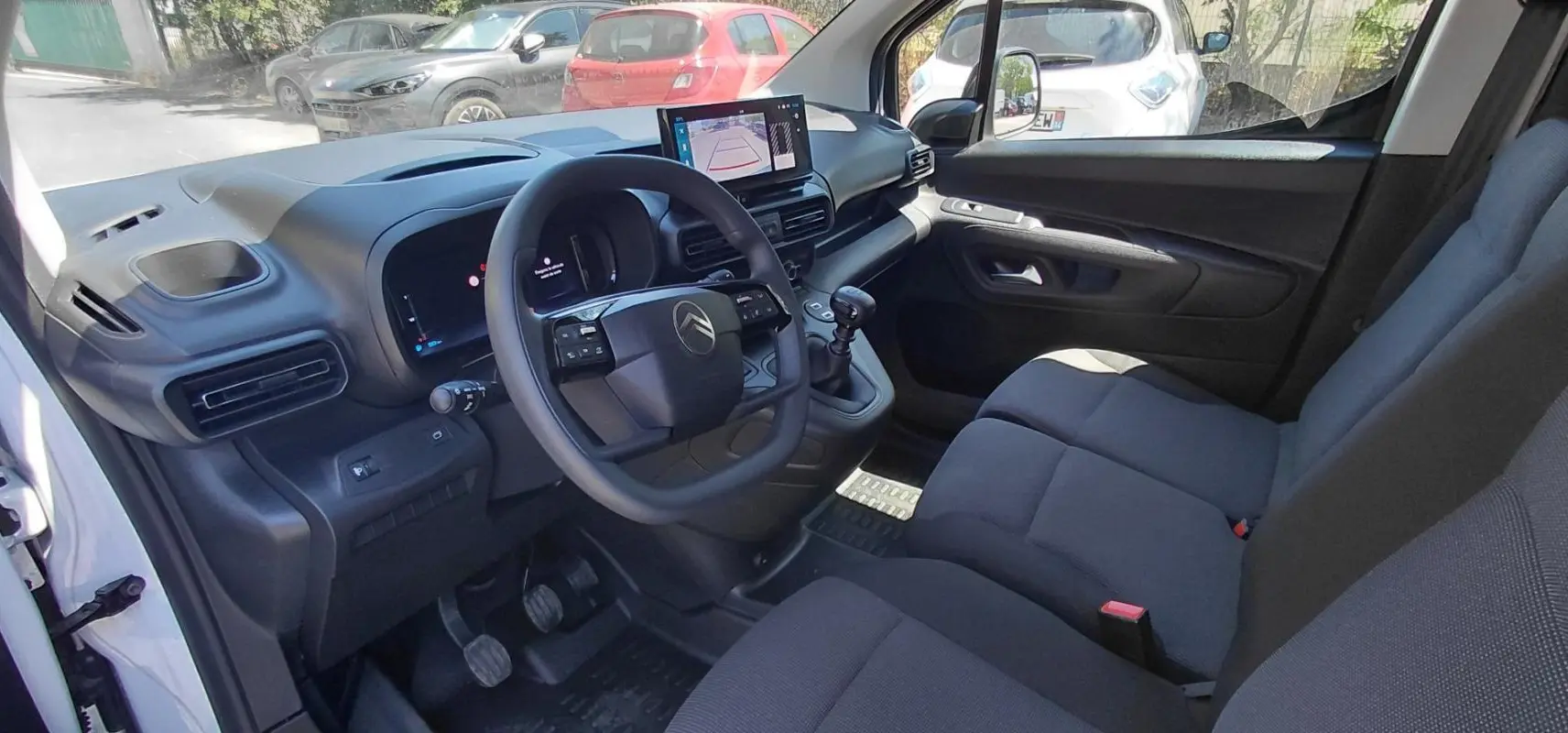 Vue intérieure côté conducteur du Citroën Berlingo blanc 2025, avec volant multifonctions et écran tactile central.