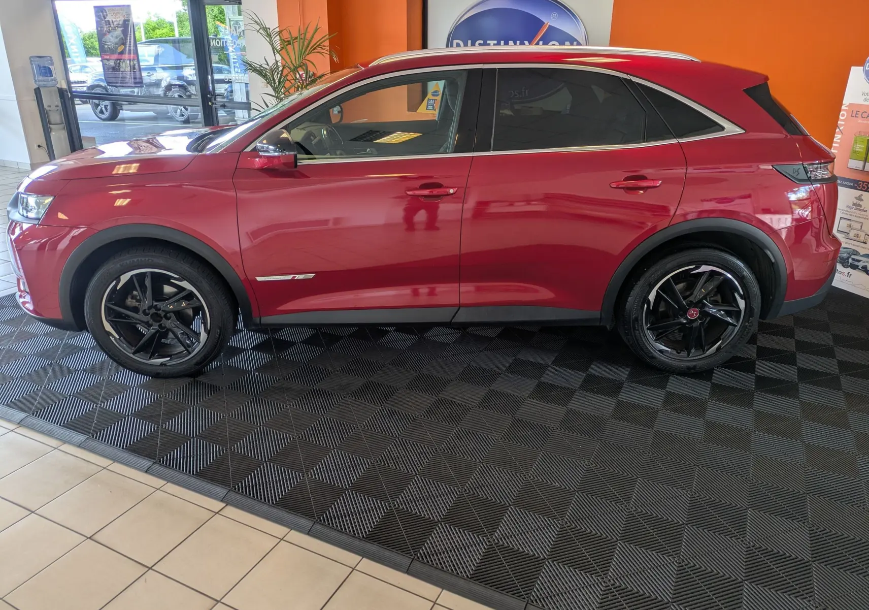 Vue de profil côté gauche d’un DS7 rouge 2019 avec attelage, soulignant ses jantes noires et son design élégant.