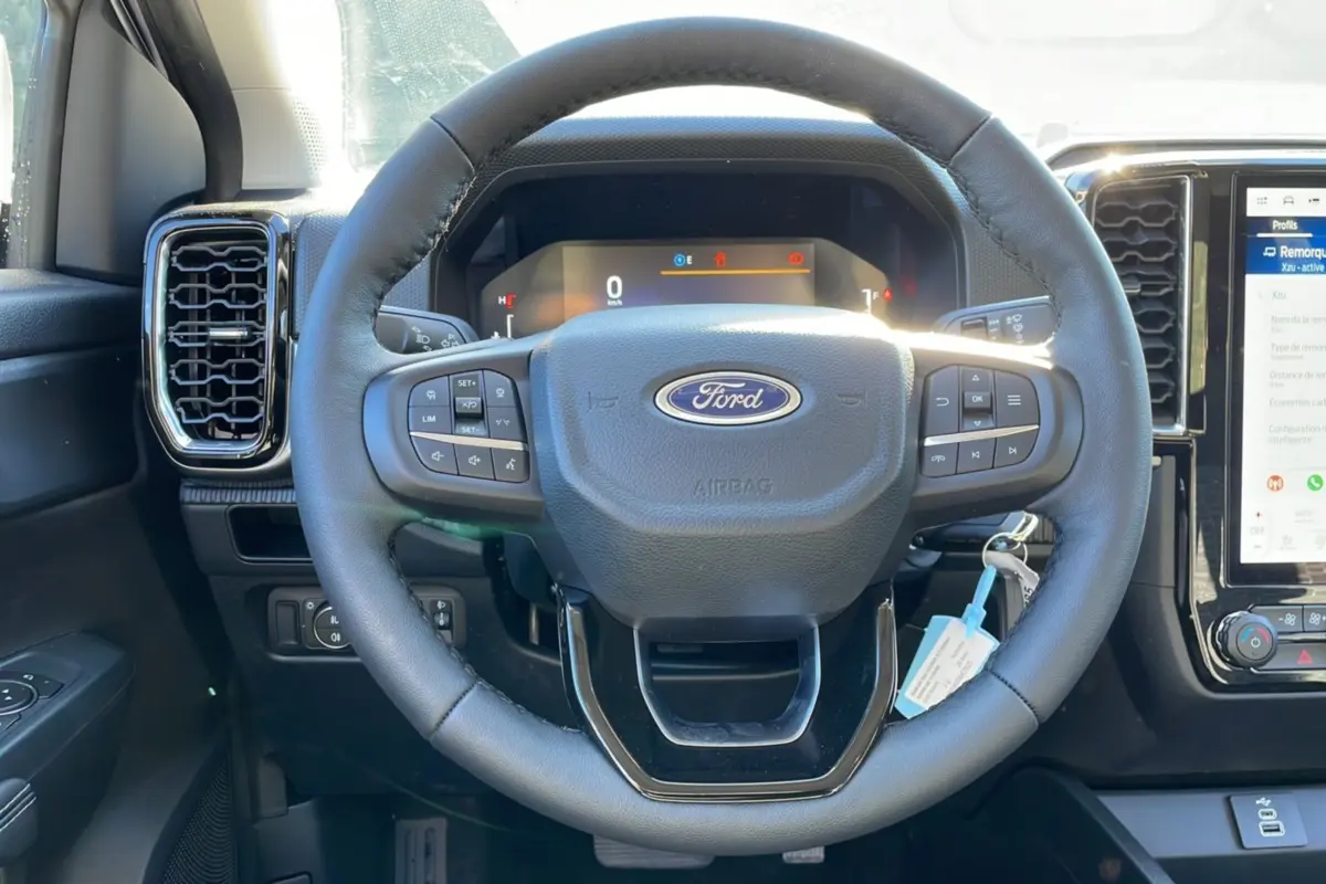 Vue rapprochée du volant cuir multifonctions noir du Ford Ranger 2025 avec tableau de bord numérique et écran tactile.
