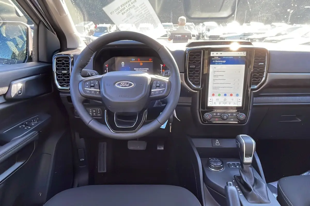 Vue intérieure frontale du tableau de bord du Ford Ranger gris, avec volant multifonctions et écran tactile vertical.