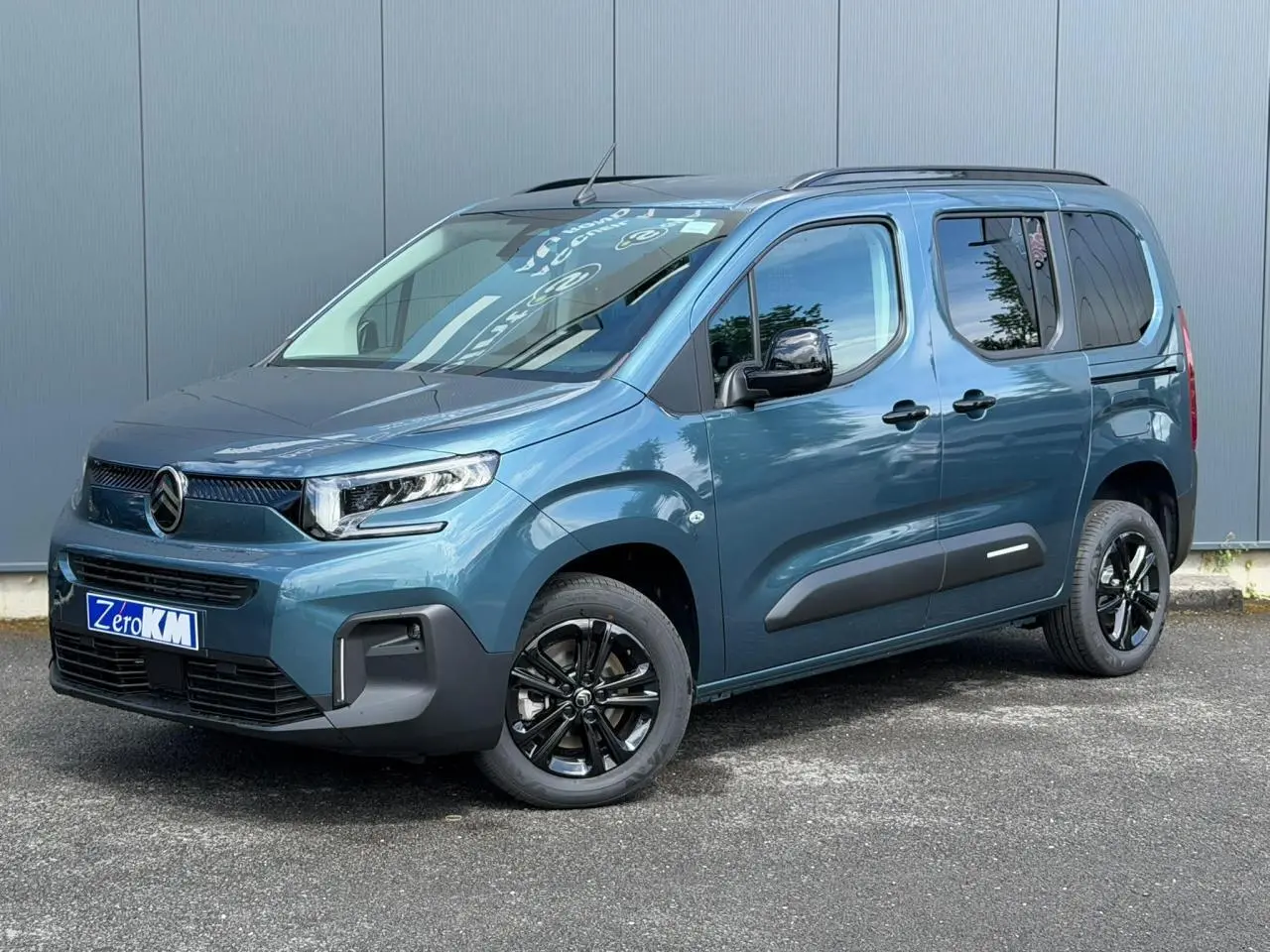 Vue 3/4 avant droite du Citroën Berlingo Multispace bleu Kiama avec jantes alliage noires et barres de toit noires.