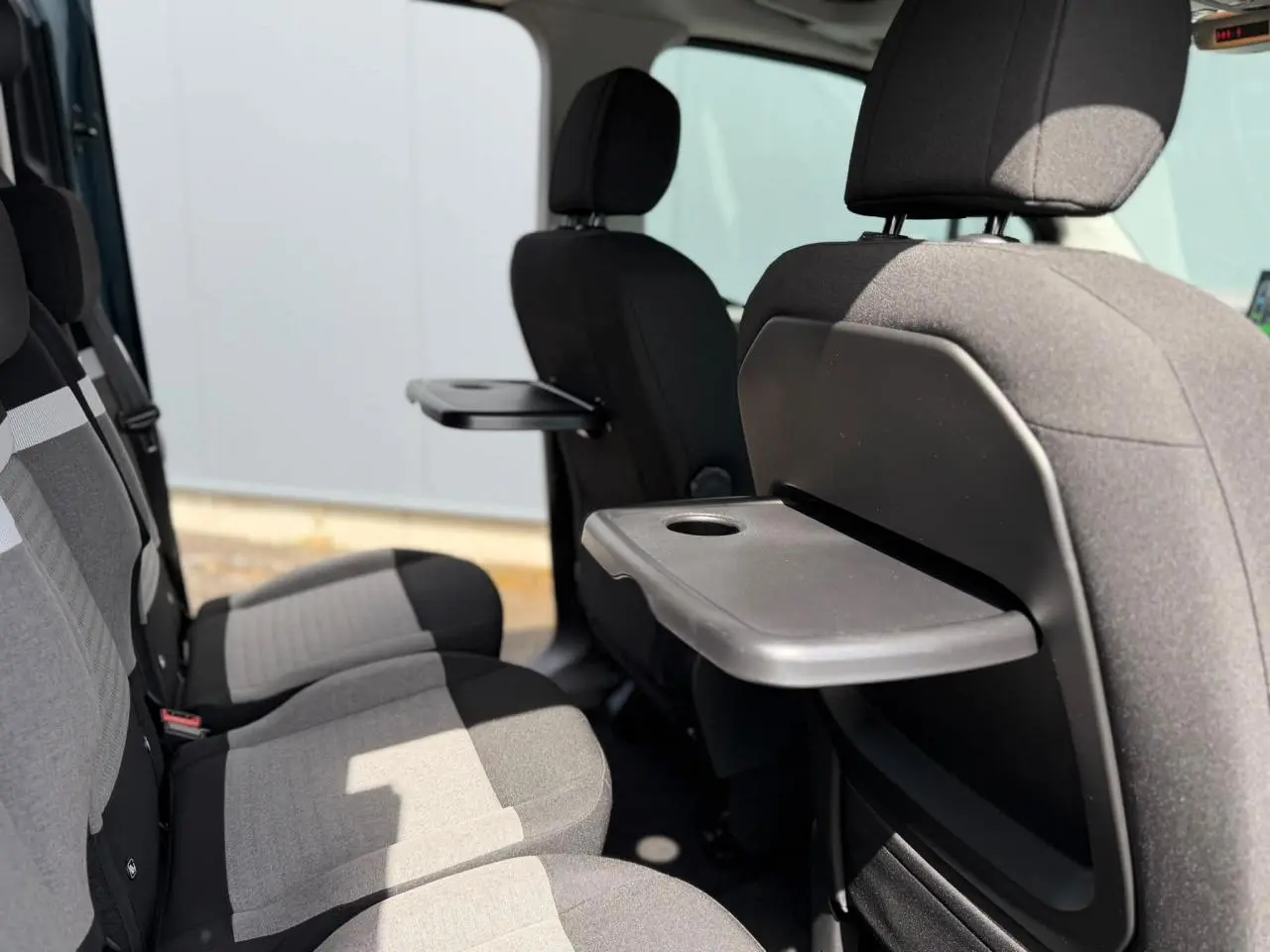 Vue latérale intérieure sur les sièges arrière gris et noirs du Citroën Berlingo Multispace avec tablette rabattable.