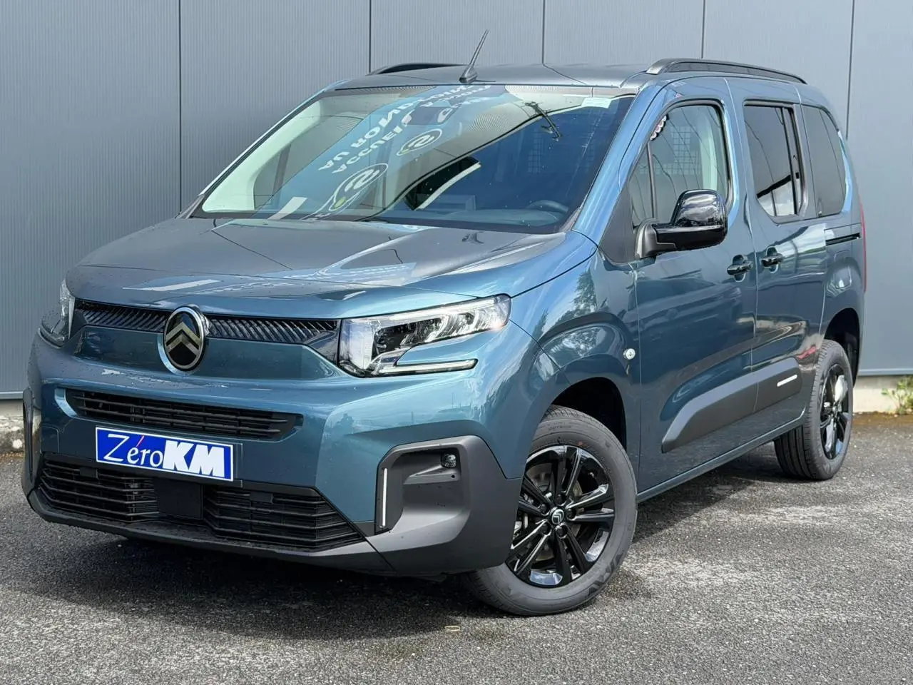 Vue 3/4 avant droite du Citroën Berlingo Multispace 2026 en bleu Kiama avec jantes alliage noires et barres de toit.
