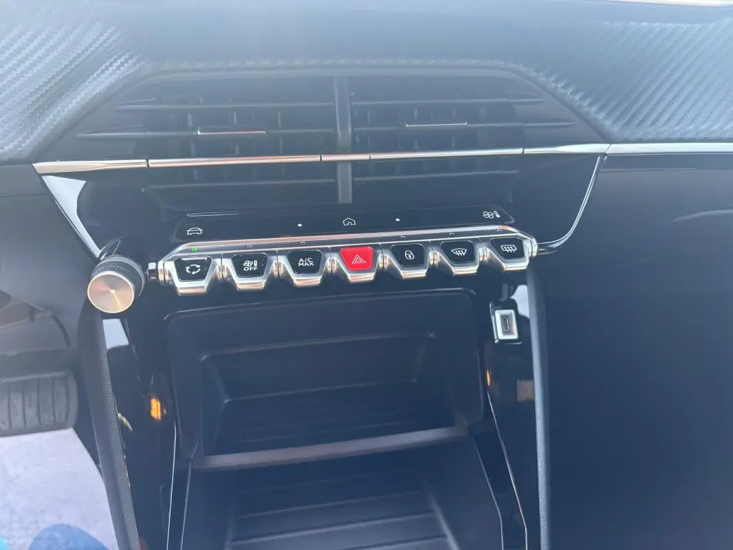 Vue rapprochée de la console centrale noire du Peugeot 2008 Hybrid 145 Style avec boutons de commande chromés.