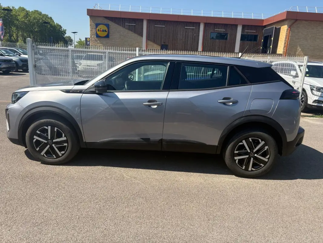 Profil droit d’un Peugeot 2008 Hybrid 145 gris 2025 avec jantes 16 pouces et toit noir contrasté.
