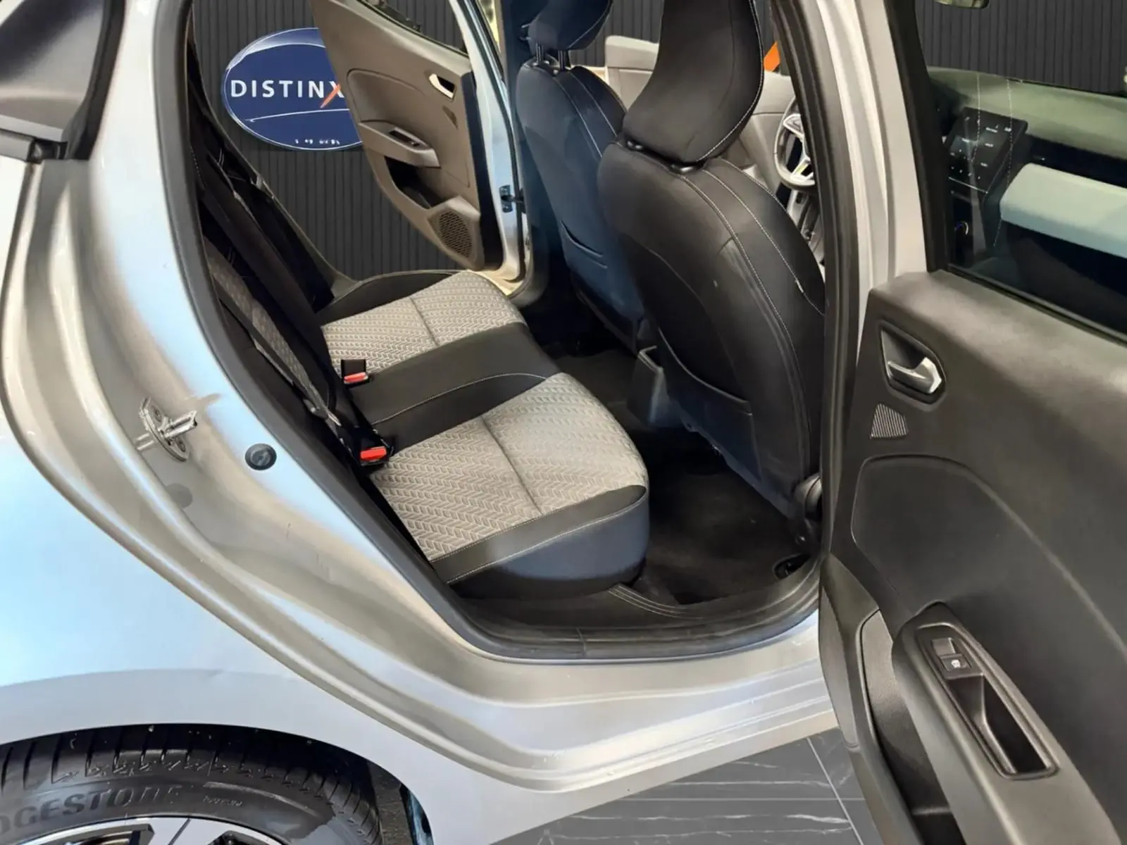 Vue intérieure côté droit arrière de la Renault Clio V gris aluminium, montrant les sièges arrière bi-ton gris et noir.