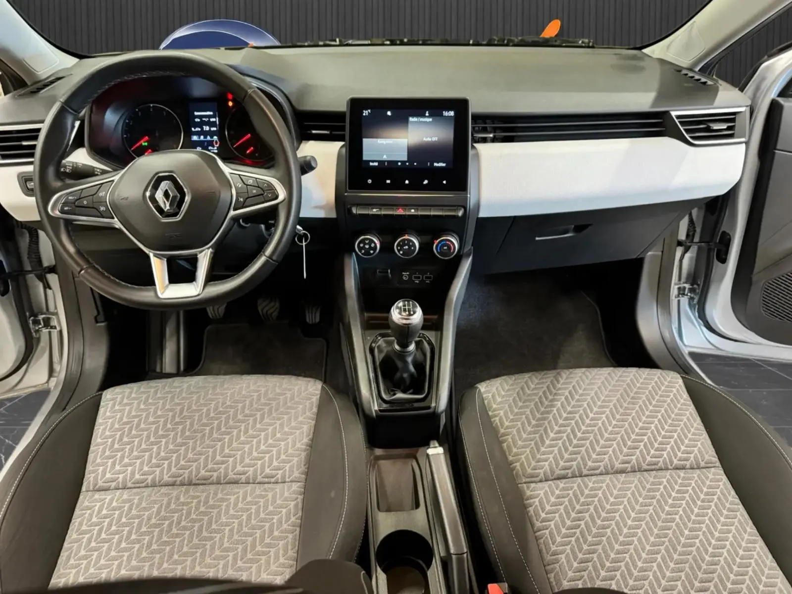 Vue intérieure frontale de la Renault Clio V 1.0 SCE 65 CH Evolution 2022, avec tableau de bord gris noir et volant multifonction.