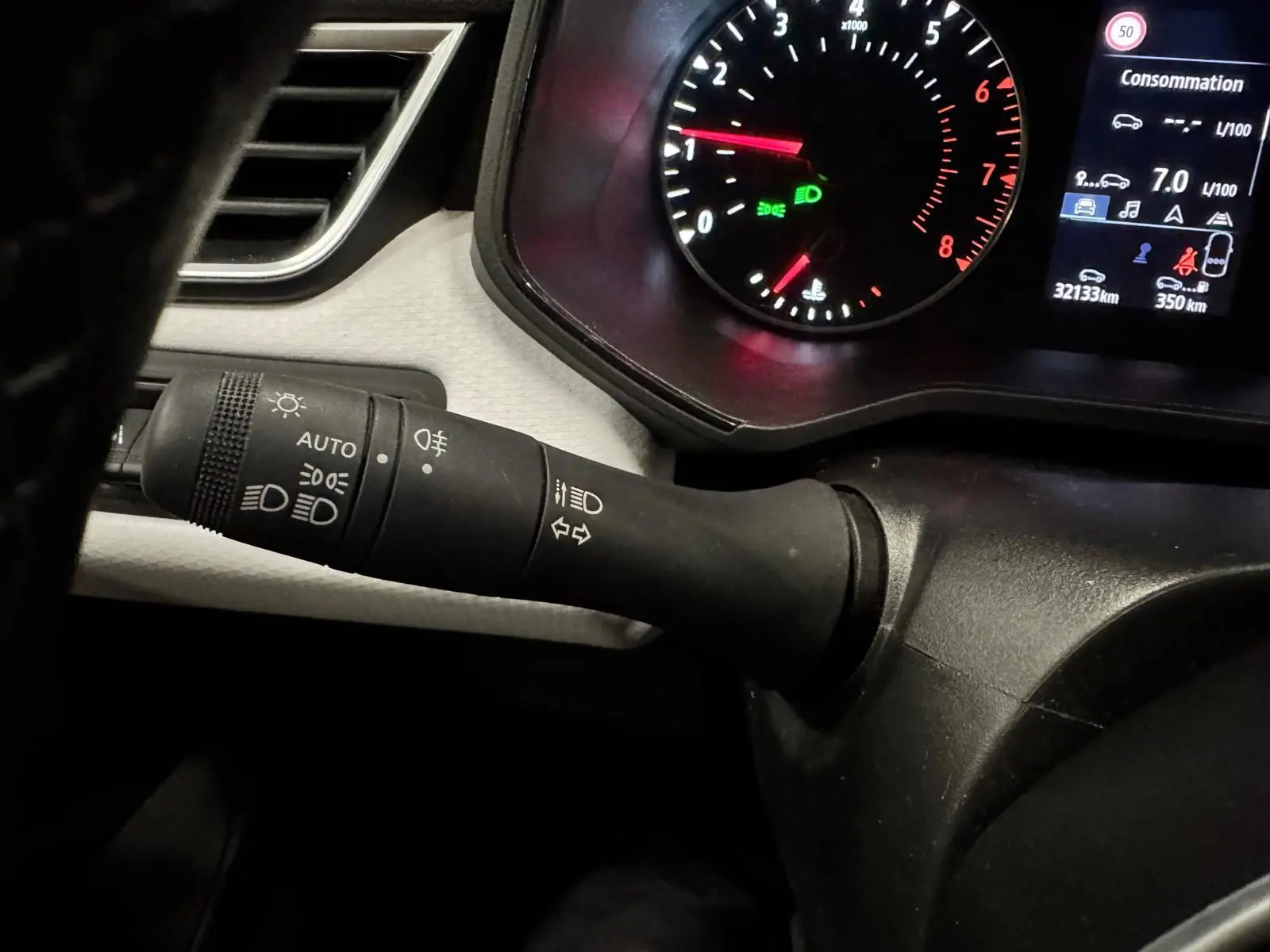 Gros plan sur la manette de phares et clignotants à gauche du tableau de bord gris noir d'une Renault Clio V 2022.