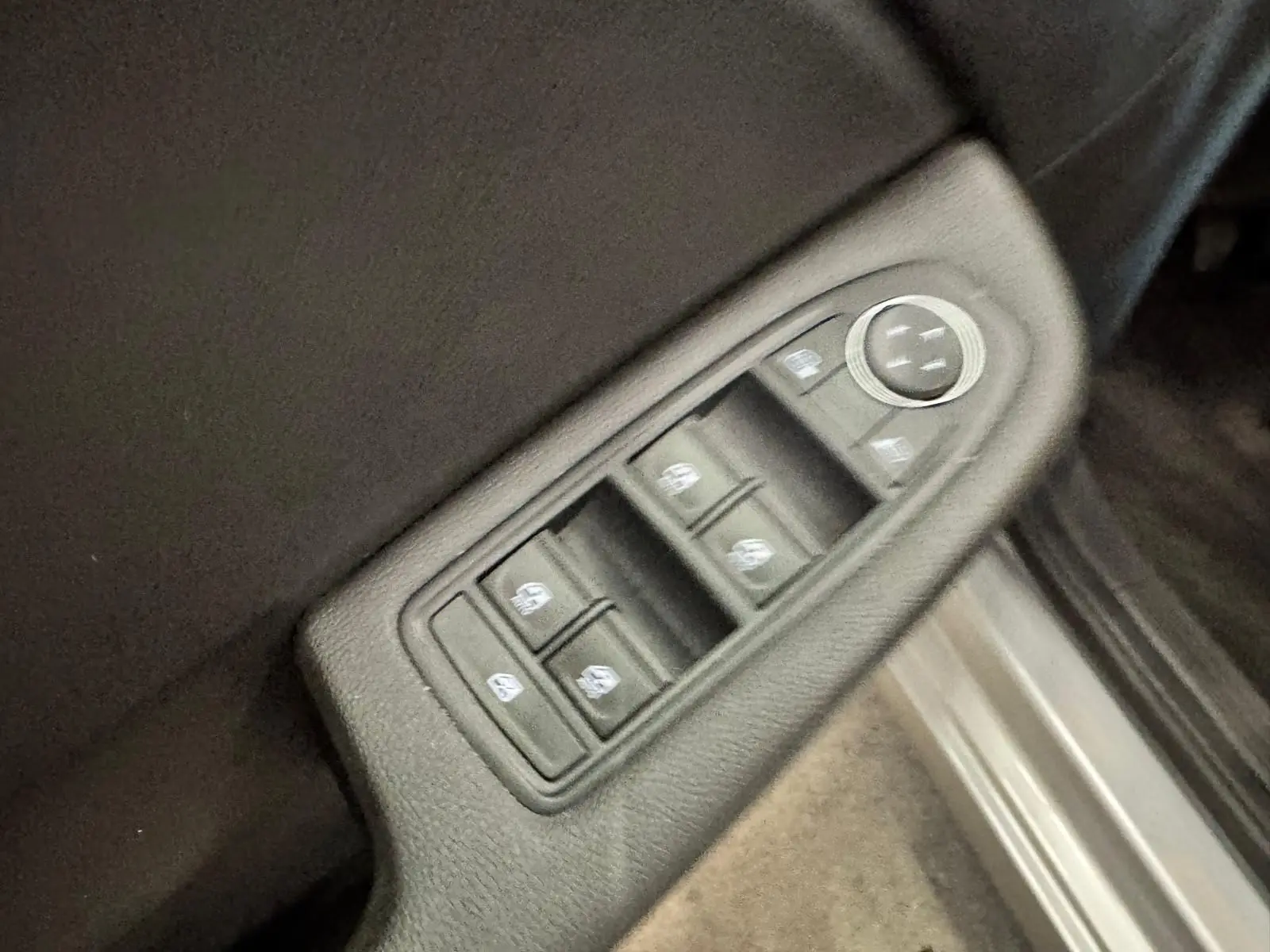 Panneau de commandes des vitres électriques et réglage des rétroviseurs côté conducteur d’une Renault Clio V gris aluminium.