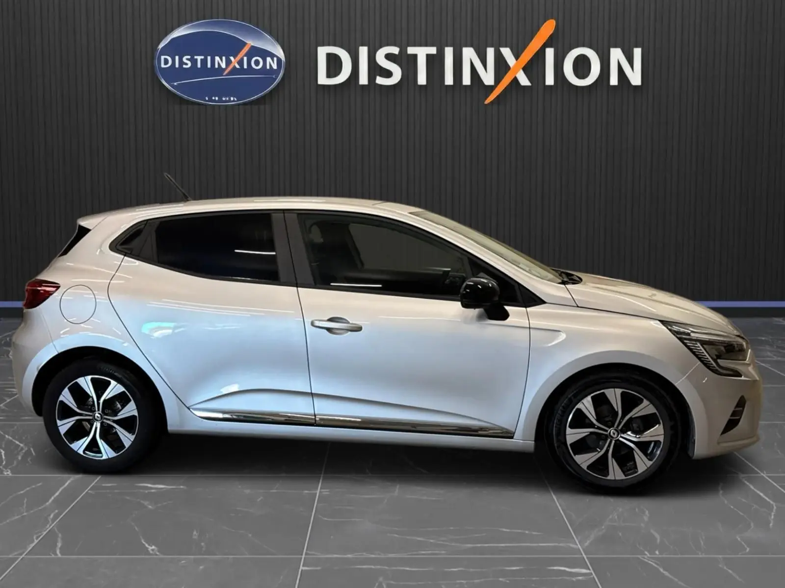Renault Clio V gris aluminium vue de profil côté gauche, avec jantes bi-ton et rétroviseurs noirs.