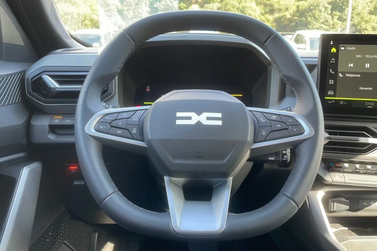 Vue rapprochée du volant cuir et du tableau de bord digital du Dacia Bigster Hybrid 150 4x4 en intérieur.