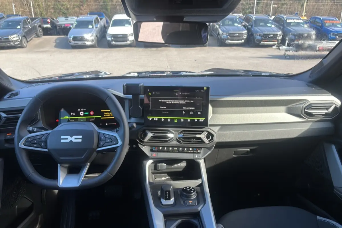 Vue intérieure avant du tableau de bord gris et volant cuir du Dacia Bigster Hybrid 150 4x4 Journey City 2026.